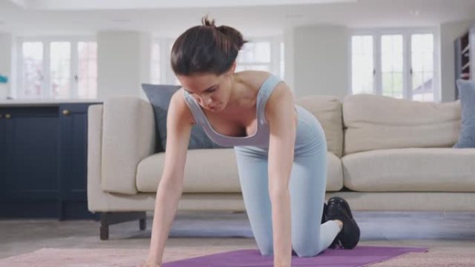 穿着健身服装的女人在休息室里做伸展运动，在垫子上锻炼