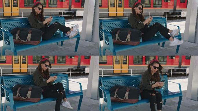 年轻女子在火车站的长凳上放松时使用手机