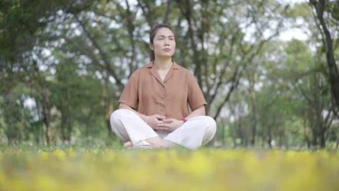 亚洲妇女早上在公园冥想瑜伽