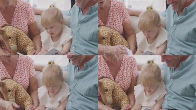 祖父母坐在沙发上与孙女一起看书的特写