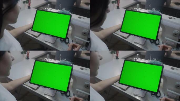 Seamstress手握手握手写笔，并在带有绿色屏幕的平板电脑上观看