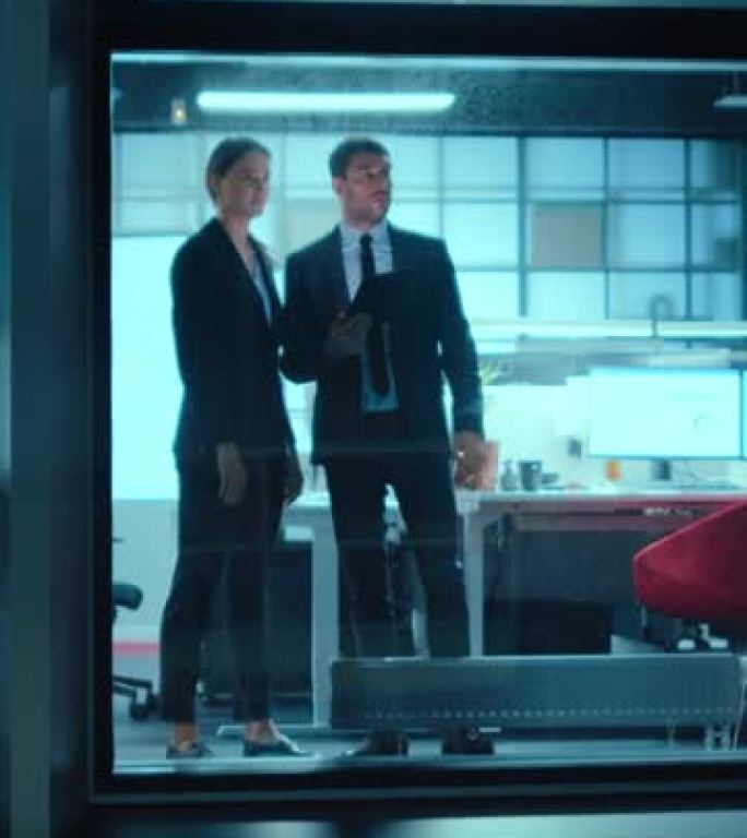 外面的镜头: 两个商业伙伴在办公室窗户旁边使用平板电脑。员工谈论财务战略。垂直屏幕方向9:16的视频