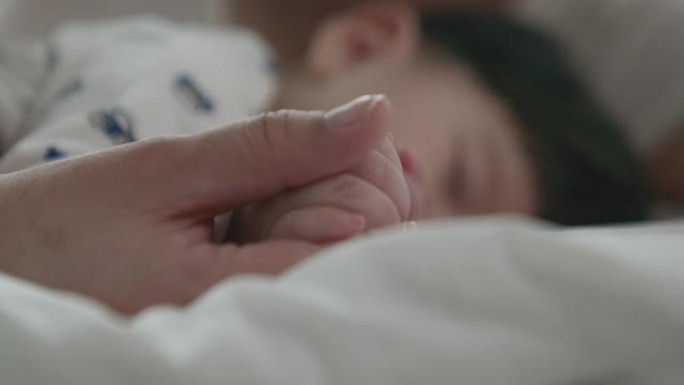 婴儿手和妈妈的软焦点。将熟睡的婴儿交在母亲的手中，近距离接触，新家庭和婴儿保护免受妈妈的概念。