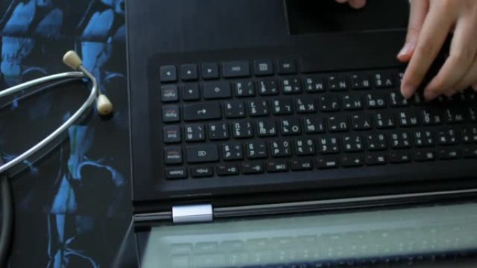 医生用听诊器和核磁共振胶片在笔记本电脑键盘上打字