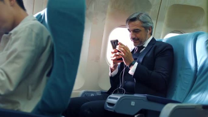 高级商人在飞行中使用手机