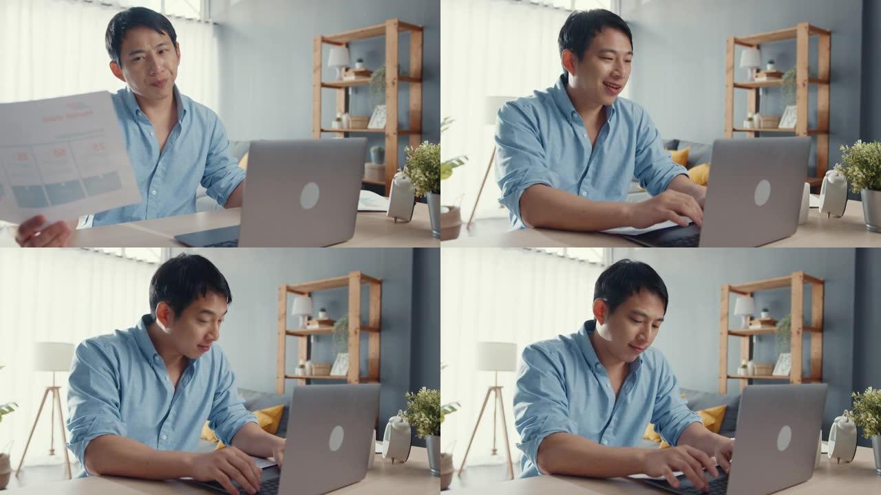 自由职业者亚洲男休闲装用笔记本电脑在家里的客厅喝咖啡。