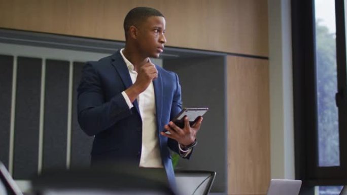 非裔美国商人在现代办公室的会议室中使用平板电脑