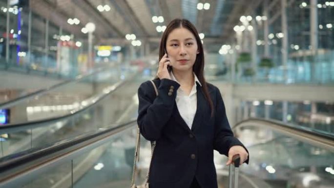 忙碌的女商人在机场上自动扶梯时用手机聊天