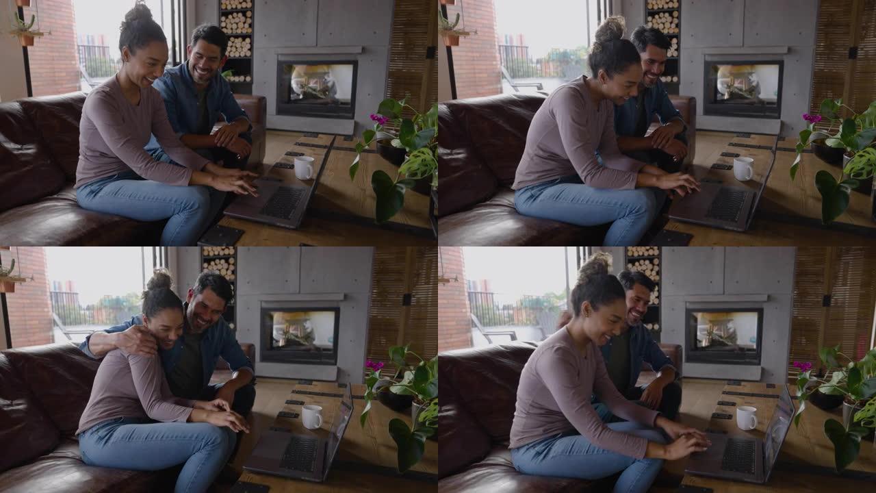 快乐的多元化夫妇坐在沙发上看着网上要买的东西，非常兴奋和拥抱