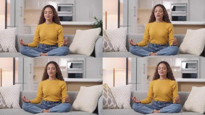 一名年轻女子在家沙发上冥想的4k视频片段