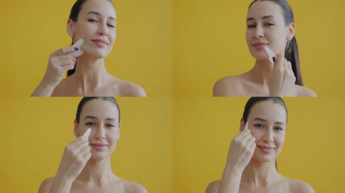 特写肖像美丽的女士按摩脸刮痧享受皮肤护理在黄色背景