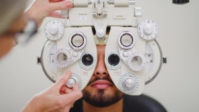 眼科医生在检查室对男性患者进行眼科检查。女性配镜师或验光师专家使用验光诊所内的检查设备检查年轻人的视