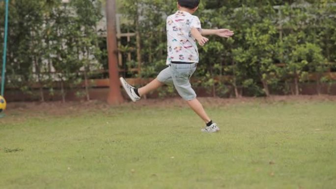 亚洲男孩在公园踢足球