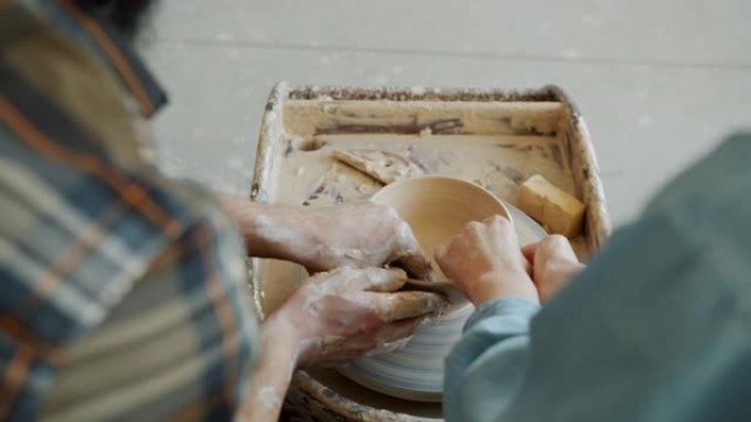背景图男性和女性双手在投掷轮上的粘土上塑形锅的慢动作