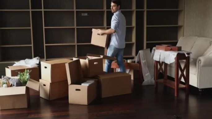 在搬迁期间，一名男子将装有物品的箱子搬到起居室