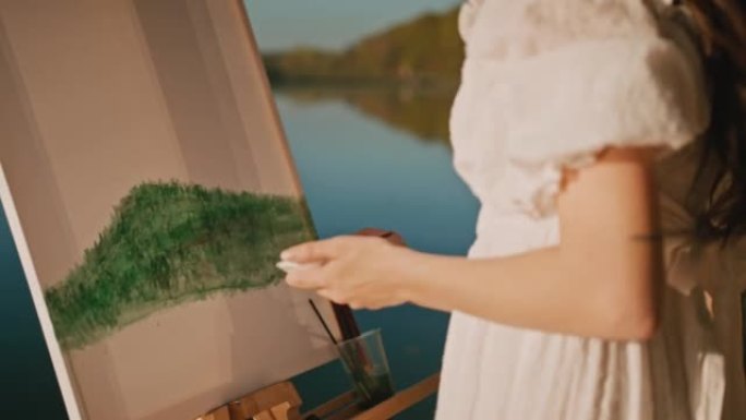 女艺术家在阳光明媚的日子在湖边的画布上绘画