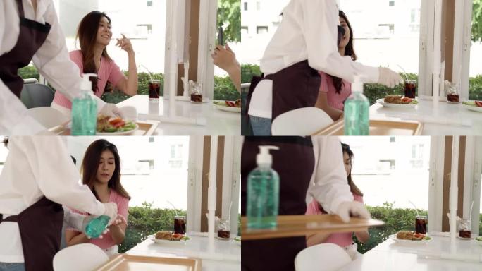 4K UHD多莉拍摄: 亚洲迷人的女服务员在用餐前向顾客推销酒精凝胶洗手液，以减少冠状病毒新型冠状病