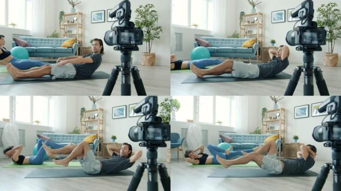 男女视频记录器在瑜伽垫上工作，在家录制网络视频