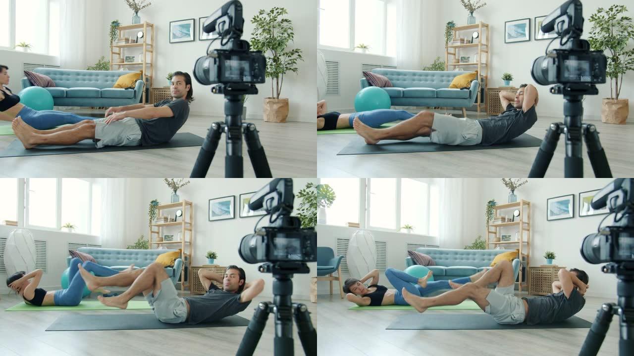 男女视频记录器在瑜伽垫上工作，在家录制网络视频