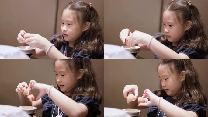 可爱的亚洲小女孩将鸡蛋切成碗