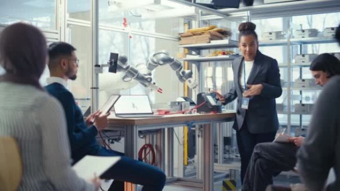 黑人专家向不同的计算机科学专家解释，而机器人肢体在她的控制下移动。人们设计自动化机器人系统概念