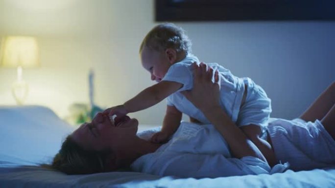 一位年轻快乐、和平的新妈妈在床上睡着之前，正在和她刚出生的男婴一起享受时光
