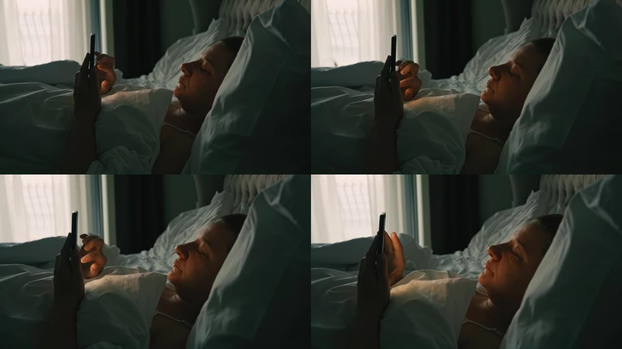 女人躺在床上，晚上使用智能手机