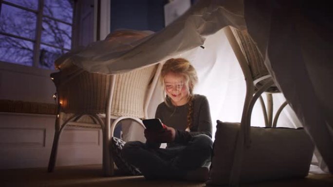 女孩坐在书房或营地，她在家玩手机