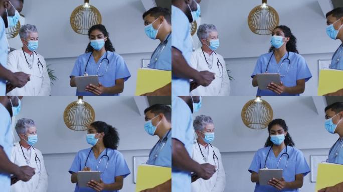多元化男女医生在口罩上使用平板电脑并在医院进行讨论