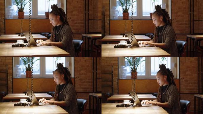 女人坐在咖啡店的桌子旁使用笔记本电脑