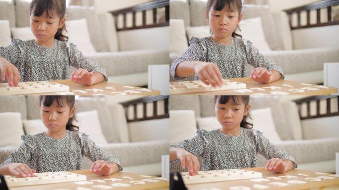小女孩在家里的客厅玩和学习字母木制玩具