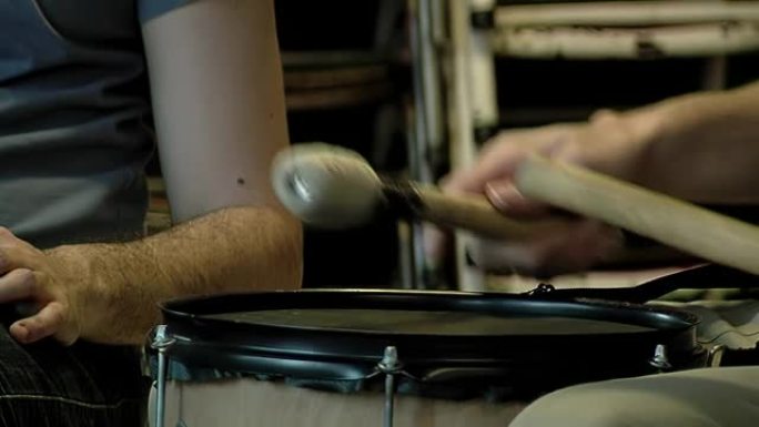 男性鼓手使用槌演奏低音鼓。特写。
