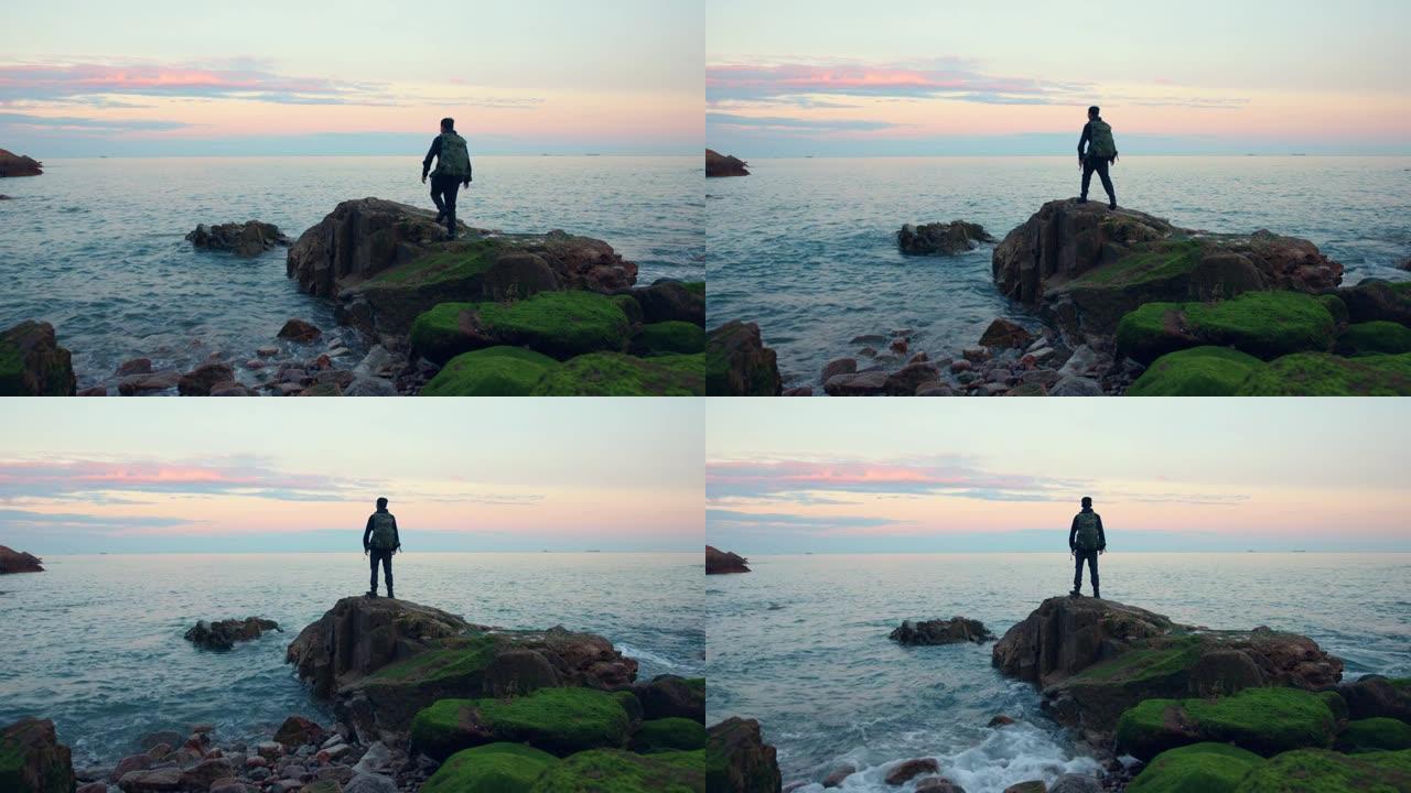 男子看着海上日落站在上面
礁石