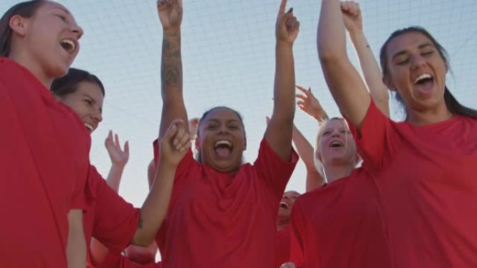 激动的女子足球队的肖像从低角度庆祝获胜的比赛