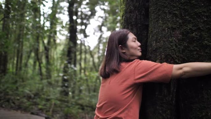 亚洲妇女在森林中拥抱一棵树，环保理念