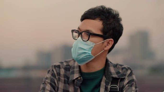 冠状病毒流行期间，年轻的亚洲男子在地铁列车上戴蓝色防护口罩。