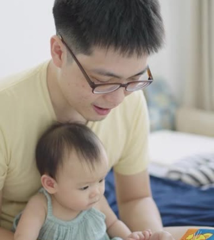 垂直-亚洲年轻的父亲和女儿一起读孩子的书