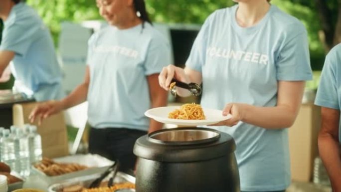一组志愿者在当地社区食品银行提供帮助，在阳光明媚的日子里向公园的低收入人群分发免费食物。慈善工作者在