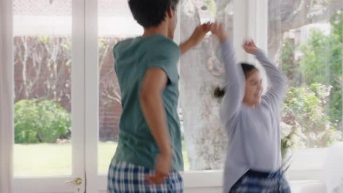 快乐的父亲和十几岁的女儿一起跳舞，享受有趣的舞蹈，享受周末穿着睡衣在家庆祝活动