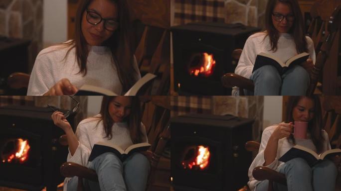 女人在家里壁炉旁的椅子上放松时看书喝茶