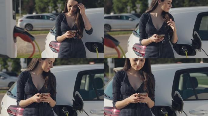 年轻女子在停车场给电动车充电时使用手机