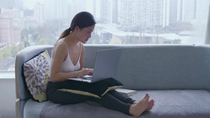 年轻的亚洲妇女在家中使用笔记本电脑