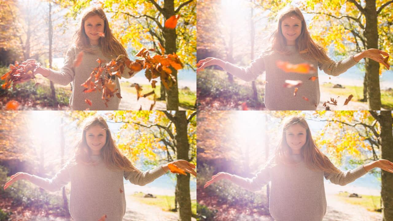 微笑的年轻女子向空中扔秋叶