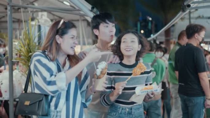 年轻的亚洲朋友在夜市享受街头美食。