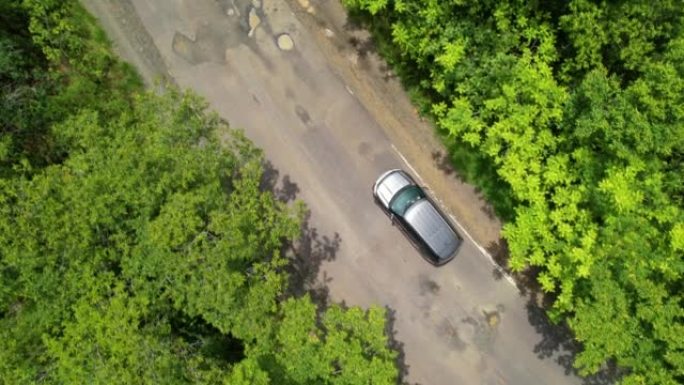 高空自顶向下:在热带乡村道路上，汽车司机在处理大的坑洼