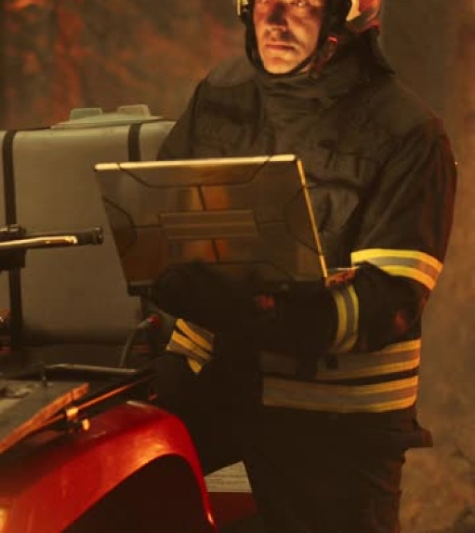 垂直屏幕: 勇敢的消防员站在ATV旁边，在森林中使用笔记本电脑，熊熊燃烧。警司或班长确保紧急情况得到