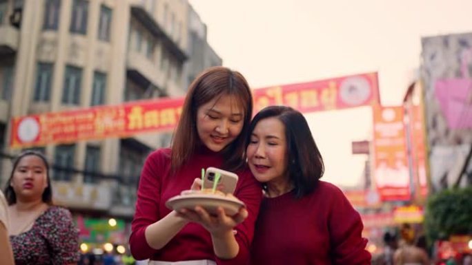 亚洲母女在农历新年在唐人街旅行和吃街头美食。
