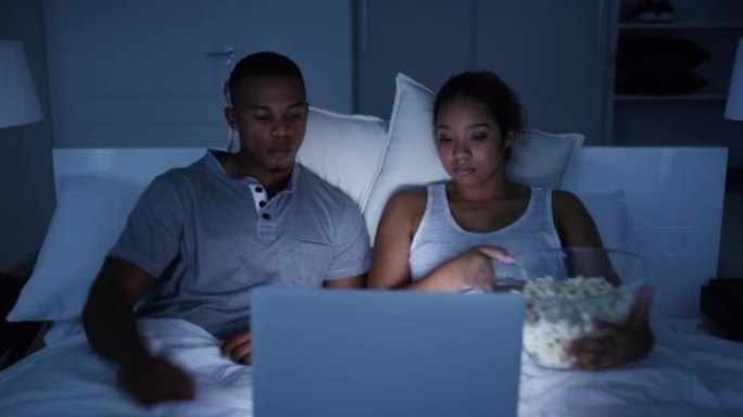 4k视频片段，一对年轻有魅力的夫妇在家里床上的笔记本电脑上看电影