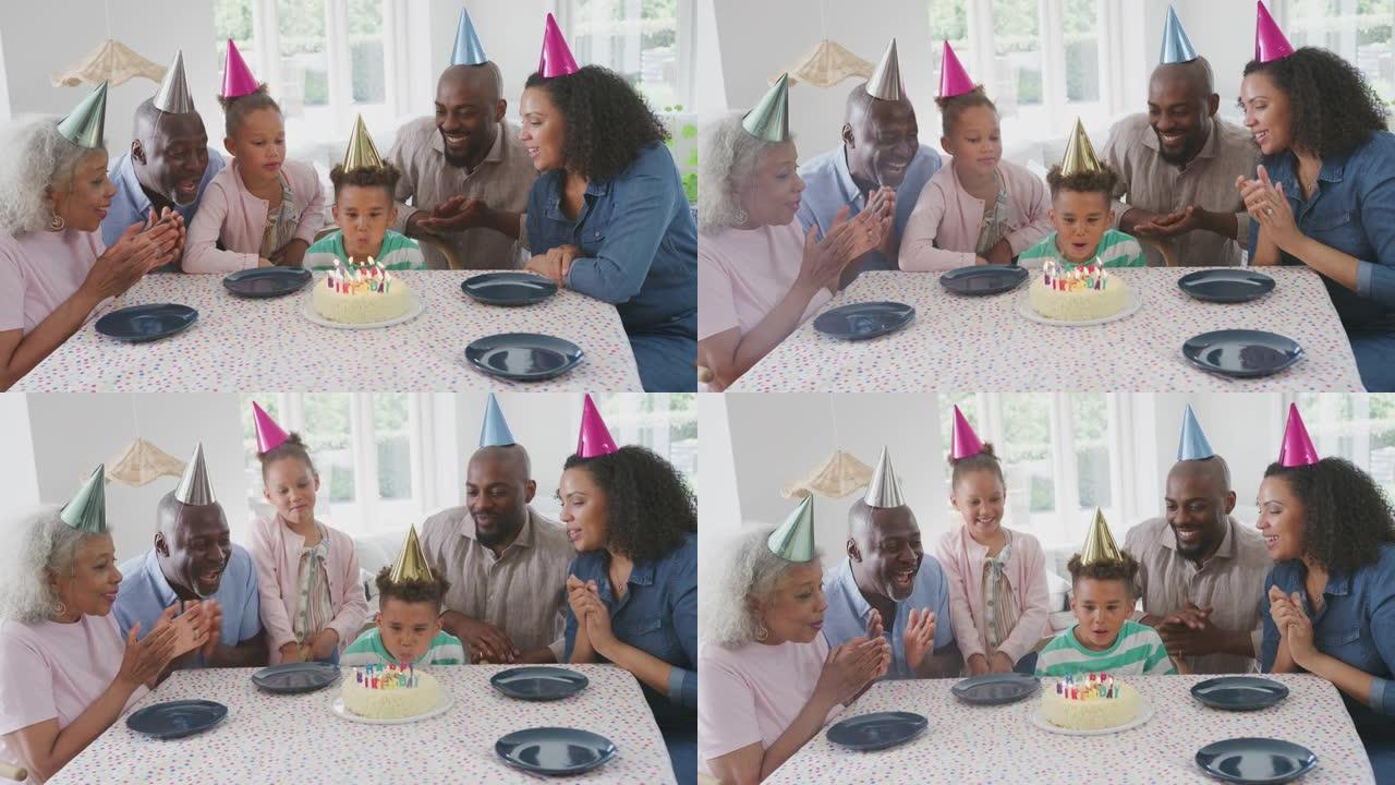 多代家庭围坐在桌子旁庆祝男孩的生日，因为他吹蜡烛