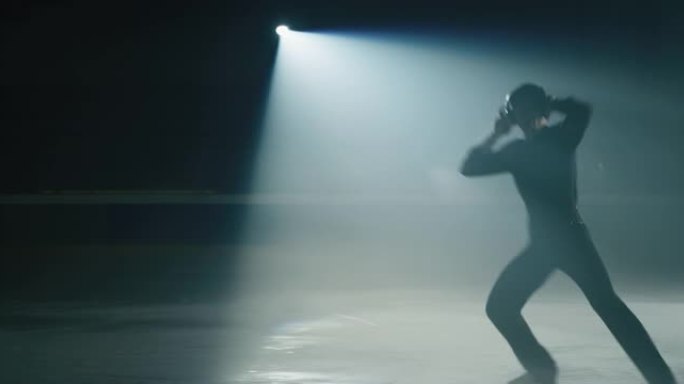 戴着耳机的年轻男花样滑冰运动员的电影镜头正在比赛开始前在溜冰场上进行舞蹈训练。技术概念，对运动和音乐
